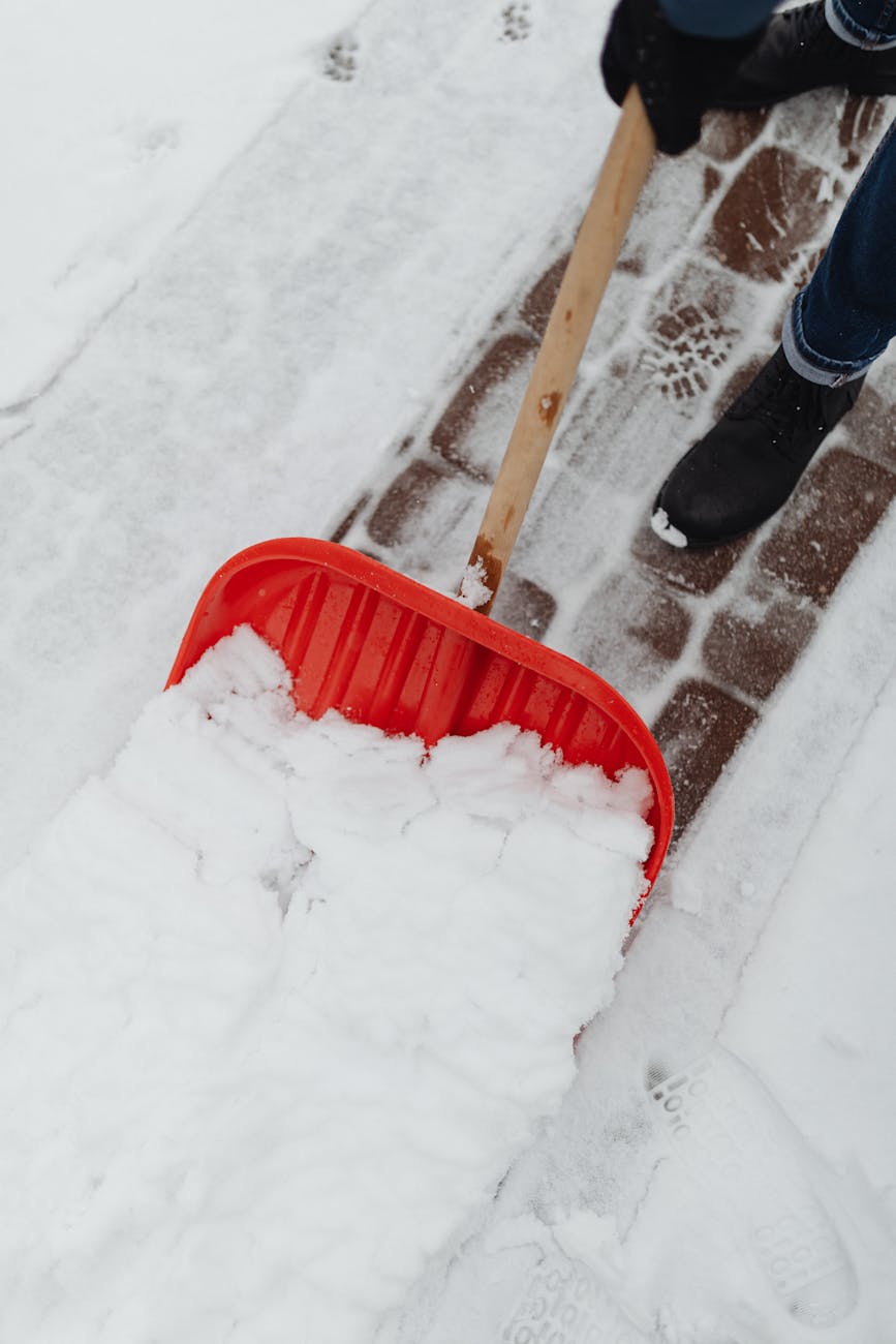 a person removing snow from the sidewalk